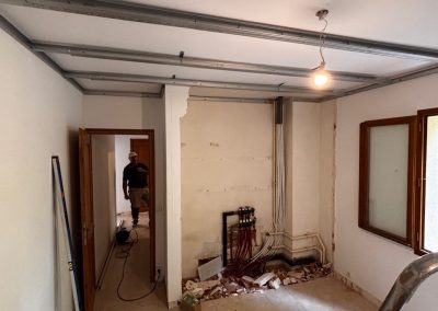 Ossature en rails métalliques pour le faux plafond dans une chambre en cours de rénovation.