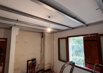 Ossature en rails métalliques pour le faux plafond dans une chambre en cours de rénovation.