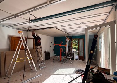 Artisans AMT installant des plaques de placoplatre BA13 au plafond lors de la rénovation.