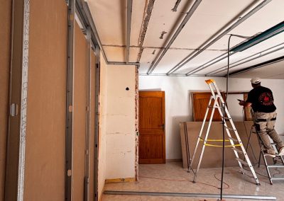 Artisan AMT en train d'installer une gaine électrique au plafond lors de la rénovation.