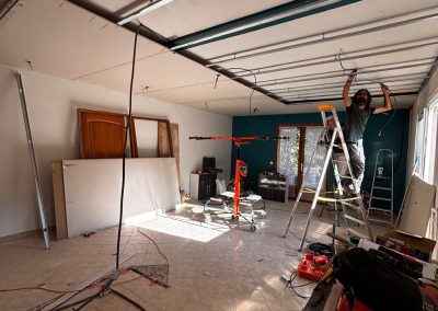 Artisan AMT en train d'installer une gaine électrique au plafond lors de la rénovation.