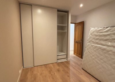 Chambre en cours de rénovation, avec parquet au sol, grand placard intégré, plafond équipé de spots LED, et un matelas posé contre le mur.