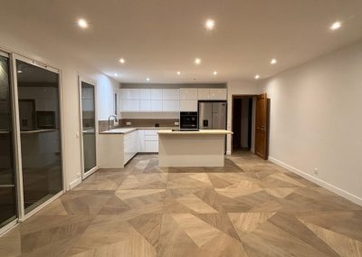 Salon et cuisine rénovés par AMT Agence Multi Travaux, avec un éclairage soigneusement positionné mettant en valeur l'ensemble du travail accompli.