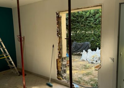 Deux barres de soubassement installées derrière le mur démoli, en préparation pour l'intégration de la baie vitrée.